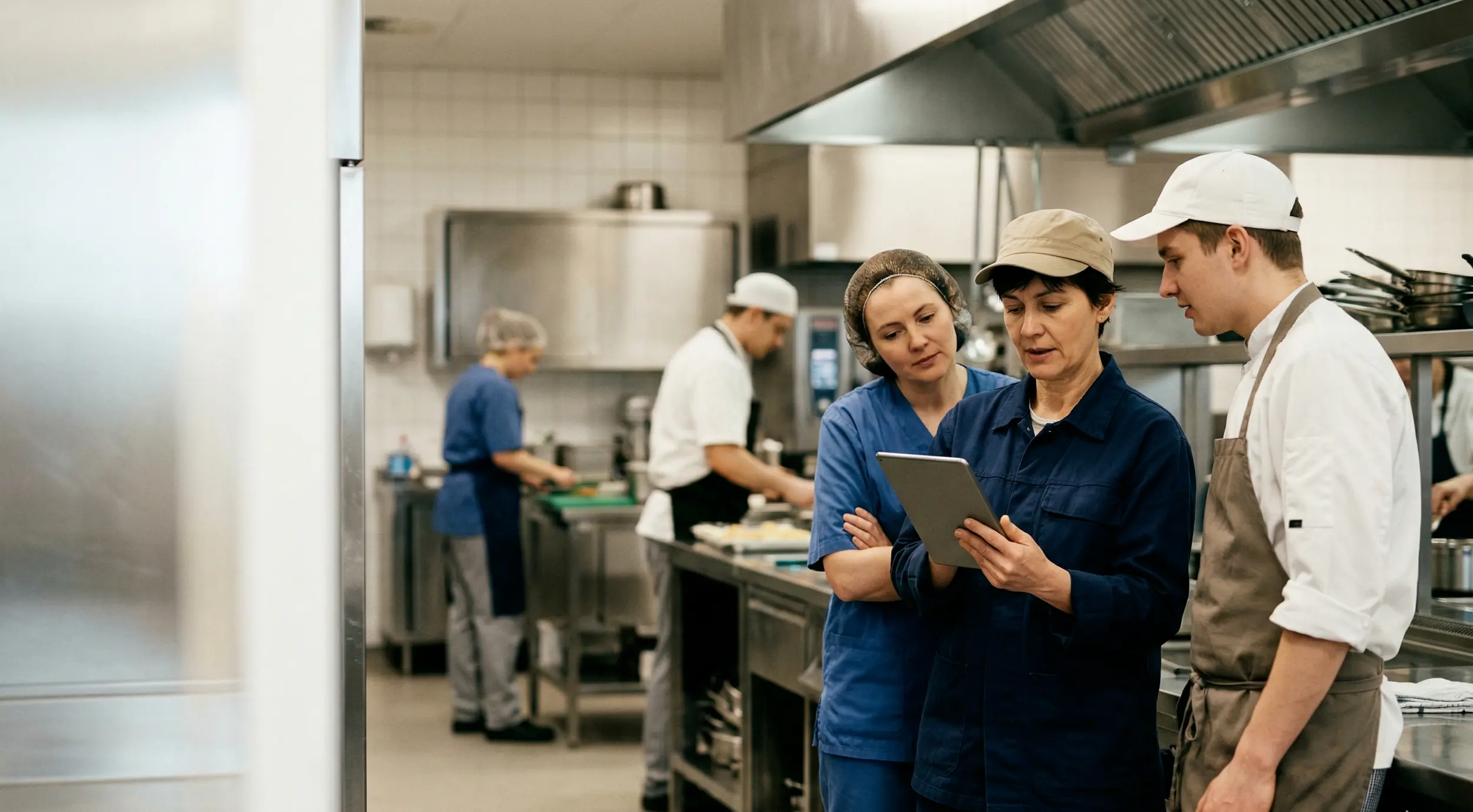 Mitarbeitende erledigen digitale HACCP-Checks mit dem Tablet in einer Großküche